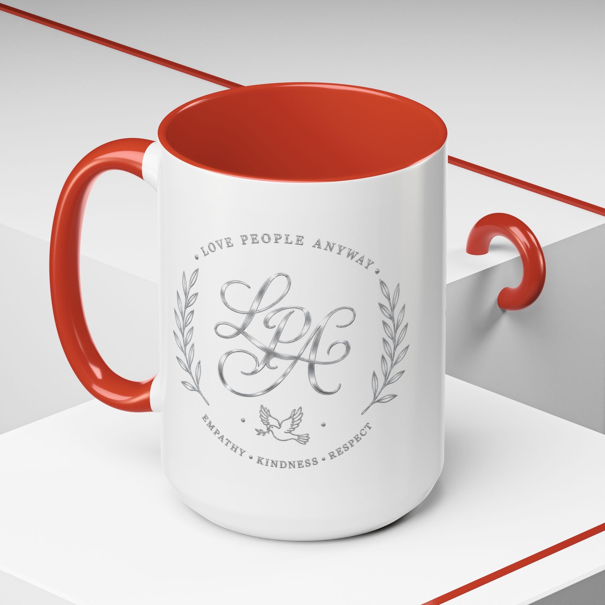 Inspirational ceramic coffee mug featuring silver “Love People Anyway” script, elegant monogram styling, decorative wreath accents, and contrasting handle and interior.