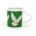 White ceramic heart-shaped handle mug featuring elegant white doves flying across a sparkling emerald green background with vibrant wraparound artwork.