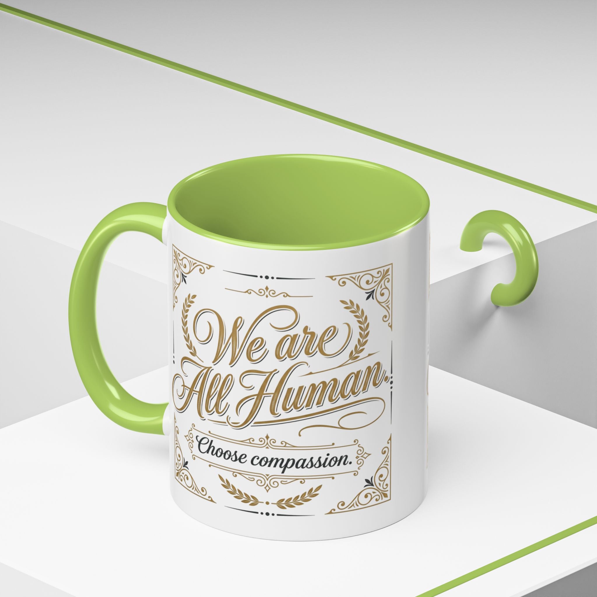 Inspirational ceramic accent coffee mug featuring “We Are All Human – Choose Compassion” in vintage-style gold lettering with decorative flourishes and black accent handle and interior.