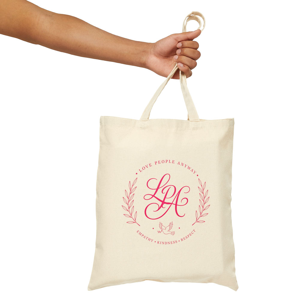 Pink monogram cotton canvas tote bag featuring the message “Love People Anyway,” laurel branches, a dove carrying an olive branch, and the words empathy, kindness, and respect in an elegant boutique design.