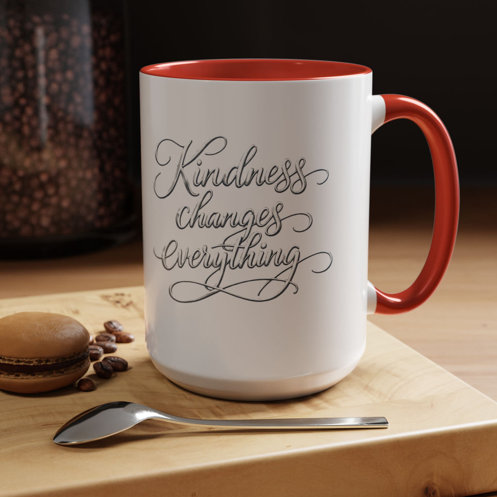 Inspirational ceramic accent coffee mug featuring elegant silver hand-lettered “Kindness Changes Everything” typography with colorful handle and interior accents.