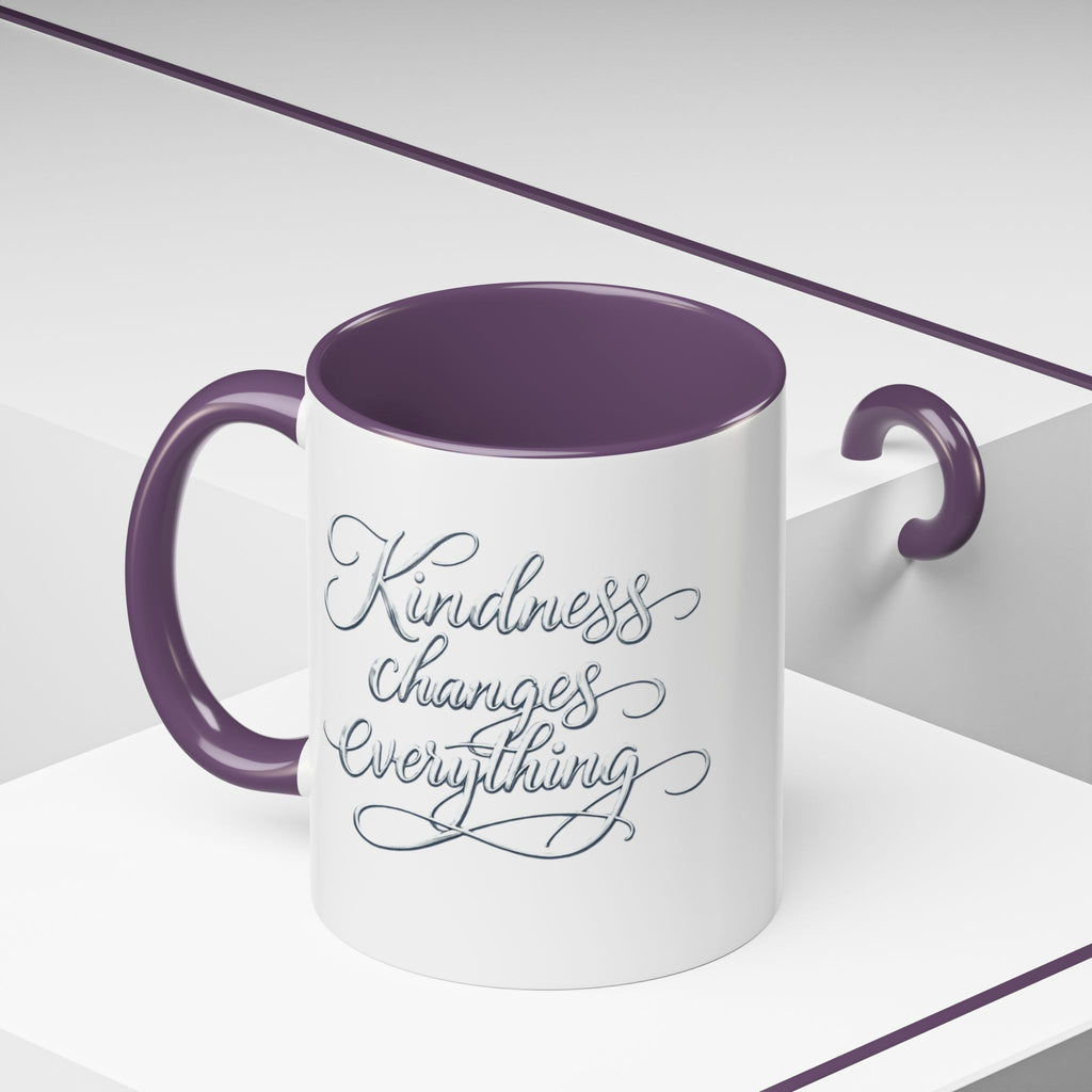 Inspirational ceramic accent coffee mug featuring elegant silver hand-lettered “Kindness Changes Everything” typography with colorful handle and interior accents.