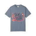 A slate blue crewneck t-shirt featuring a colorful graphic on the front with the text 'Faith will always carry you' in stylized script, decorated with pink, orange, and purple butterflies and floral elements.
