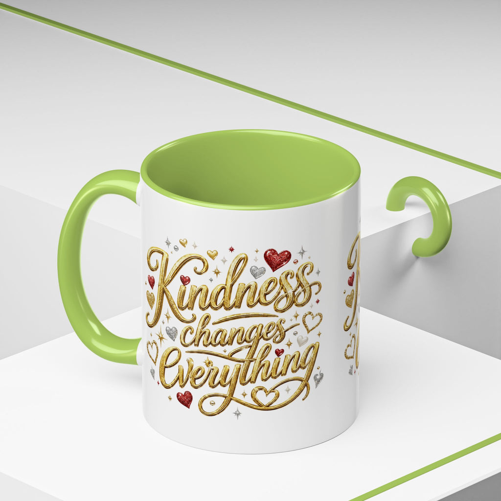 Inspirational ceramic coffee mug featuring the hand-lettered message “Kindness Changes Everything” with gold flourishes, hearts, and colorful accent handle and interior.