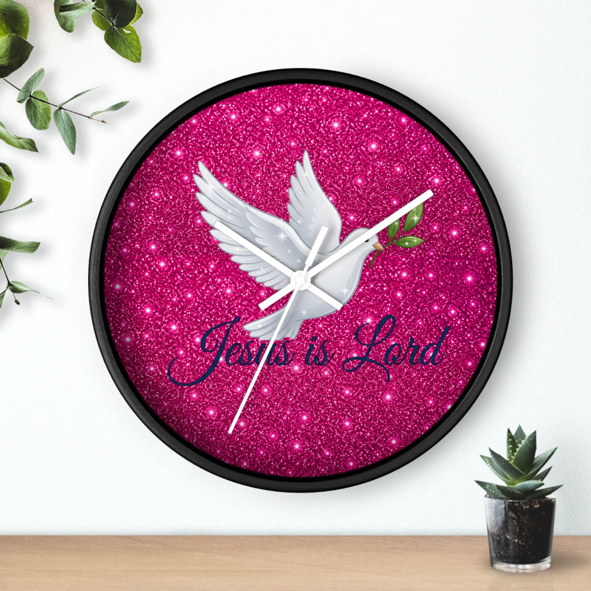 Round wall clock featuring a white dove carrying an olive branch with the words "Jesus Is Lord" on a sparkling pink background, finished with a wood frame and silent quartz movement.