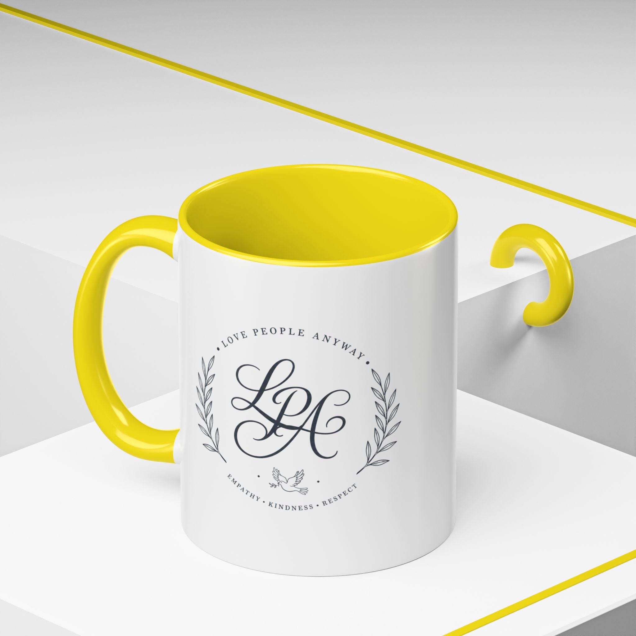 Personalized ceramic accent coffee mug featuring a custom monogram crest and the inspirational message “Love People Anyway” with colorful handle and interior accents.
