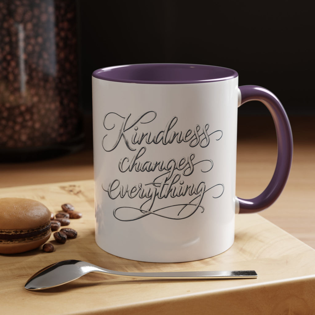 Inspirational ceramic accent coffee mug featuring elegant silver hand-lettered “Kindness Changes Everything” typography with colorful handle and interior accents.