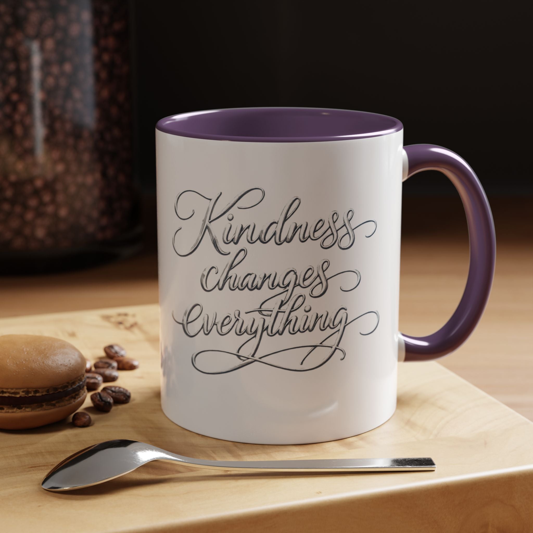 Inspirational ceramic accent coffee mug featuring elegant silver hand-lettered “Kindness Changes Everything” typography with colorful handle and interior accents.