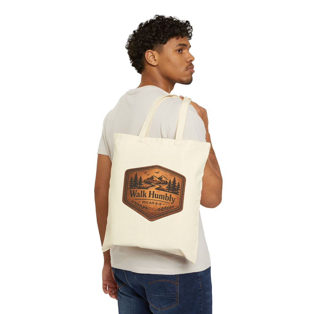 Rustic Christian cotton canvas tote bag featuring Micah 6:8 and the message “Walk Humbly,” with vintage mountain landscape artwork, pine trees, birds, and a winding trail in a leather-patch style design.