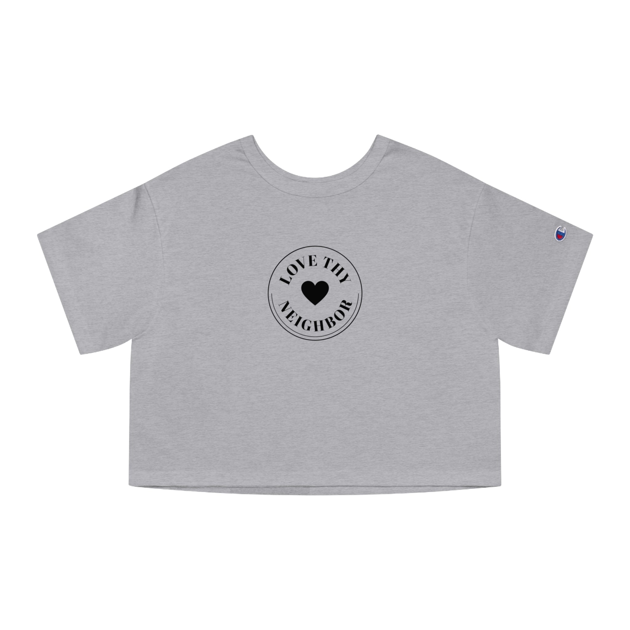 A light heather gray short-sleeve crop top t-shirt featuring a black circular graphic on the chest that reads 'LOVE THE NEIGHBOR' around a central heart, with a small purple Champion logo on the left sleeve.