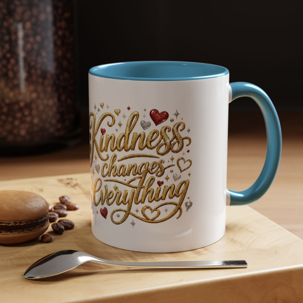 Inspirational ceramic coffee mug featuring the hand-lettered message “Kindness Changes Everything” with gold flourishes, hearts, and colorful accent handle and interior.
