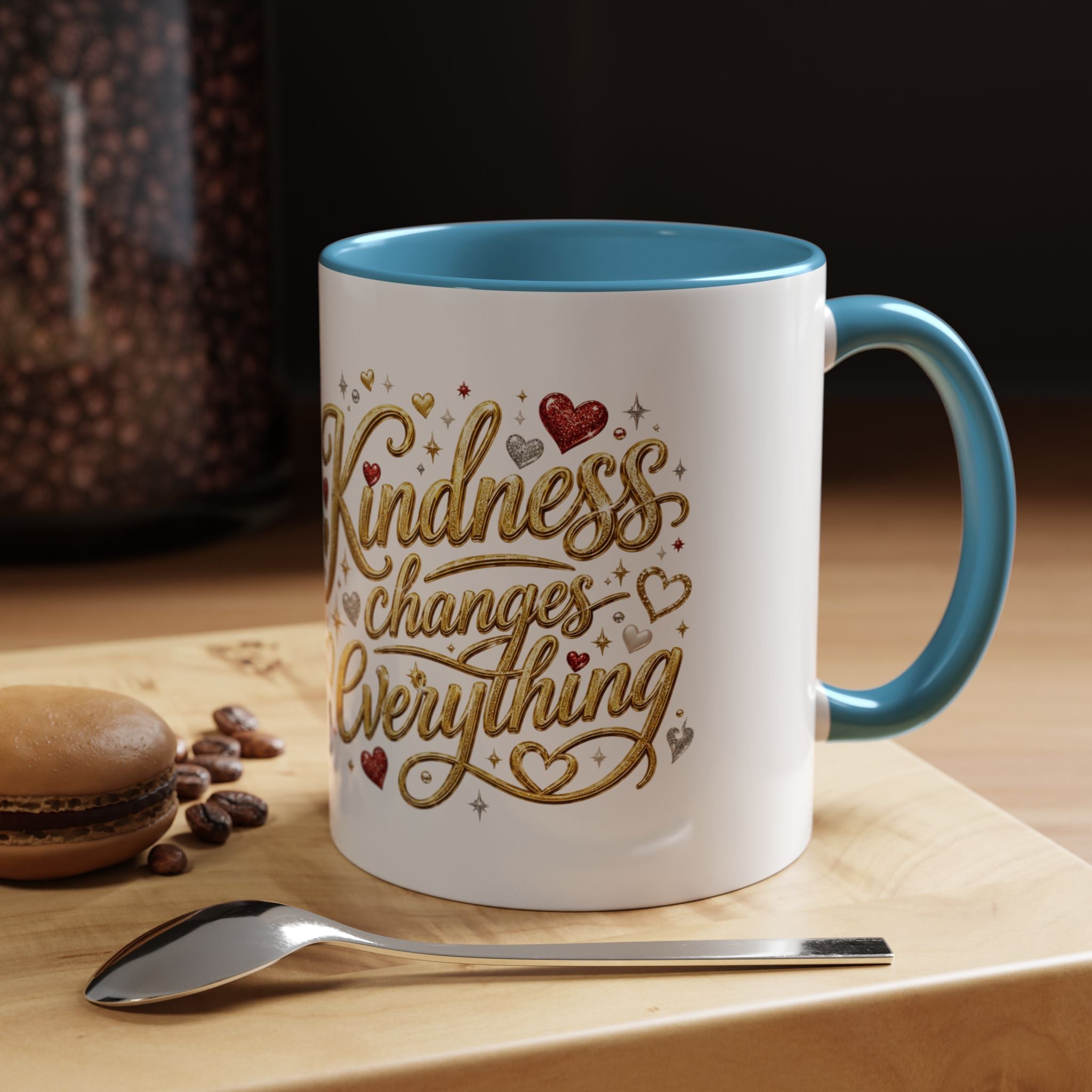 Inspirational ceramic coffee mug featuring the hand-lettered message “Kindness Changes Everything” with gold flourishes, hearts, and colorful accent handle and interior.